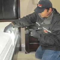 Bed bug inspection technician checking a mattress and bed frame for signs of infestation in Fargo, ND