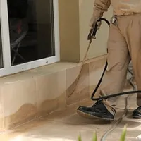 General pest control technician spraying exterior perimeter around a home in Fargo, ND