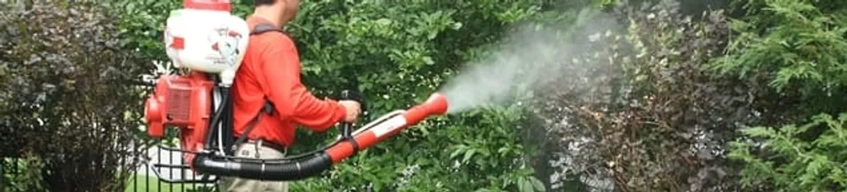 Mosquito control technician fogging shrubs and landscaping for mosquito treatment in Fargo, ND