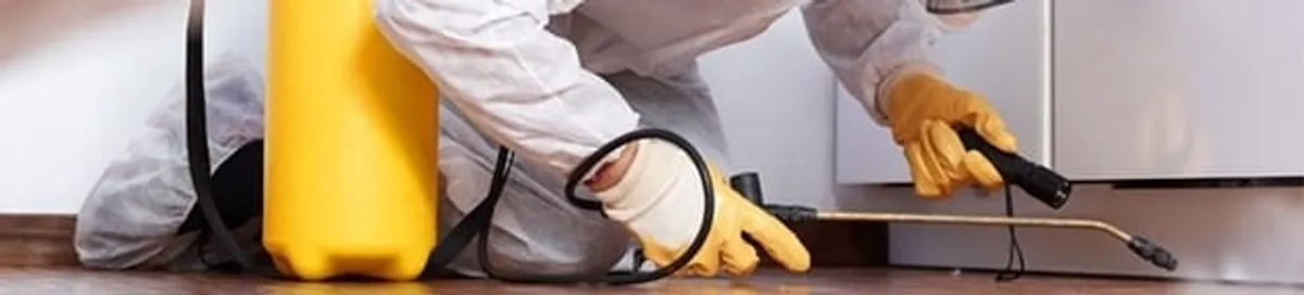 Roach exterminator treating cracks and crevices along kitchen baseboards in Fargo, ND
