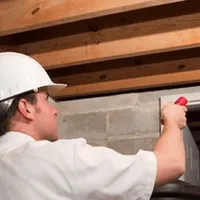 Termite inspection technician checking a basement wall and framing for termite activity in Fargo, ND